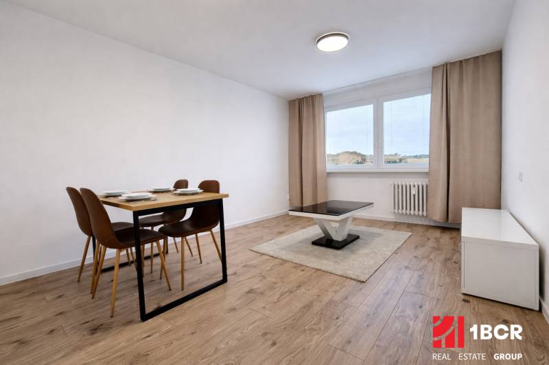 Jídelní stůl a konferenční stolek na podlaze s dřevěným dekorem v 2pokojovém bytě.
