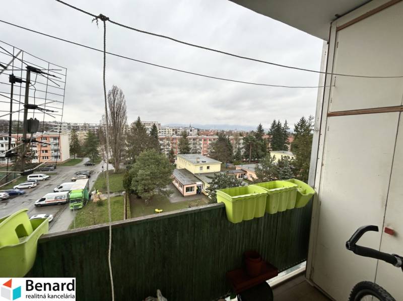 Pohled z balkonu 3pokojového bytu na Říjnové ulici v Prešově, parkoviště a zeleň.