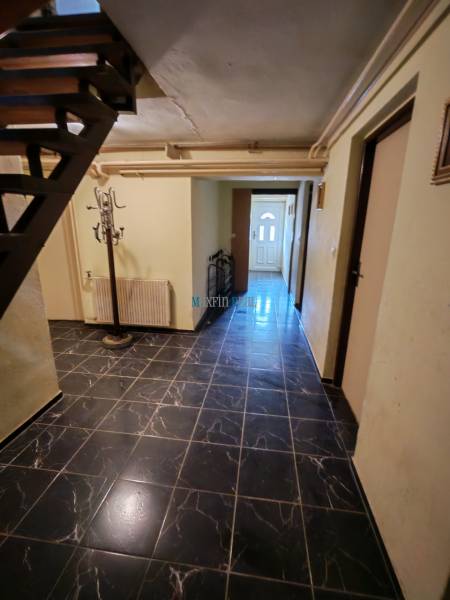 Interiér s černými obkladovými dlaždicemi a schodištěm v rodinném domě.