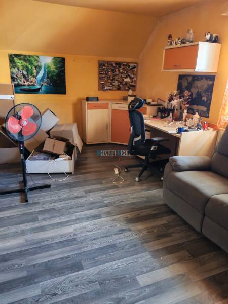 Pokoj v rodinném domě s pracovním stolem, židlí a podlahou s dřevěným dekorem.