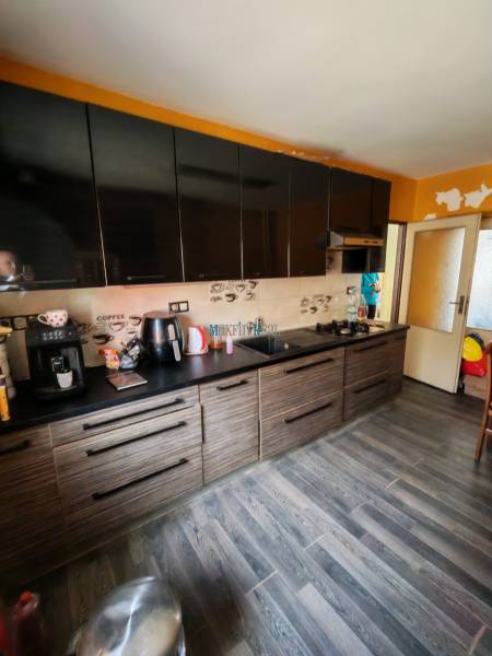 Kuchyně s černými skříňkami a podlahou s dřevěným dekorem v rodinném domě.