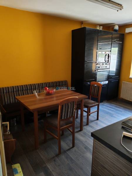 Jídelna v rodinném domě s dřevěným stolem, židlemi a podlahou s dřevěným dekorem.