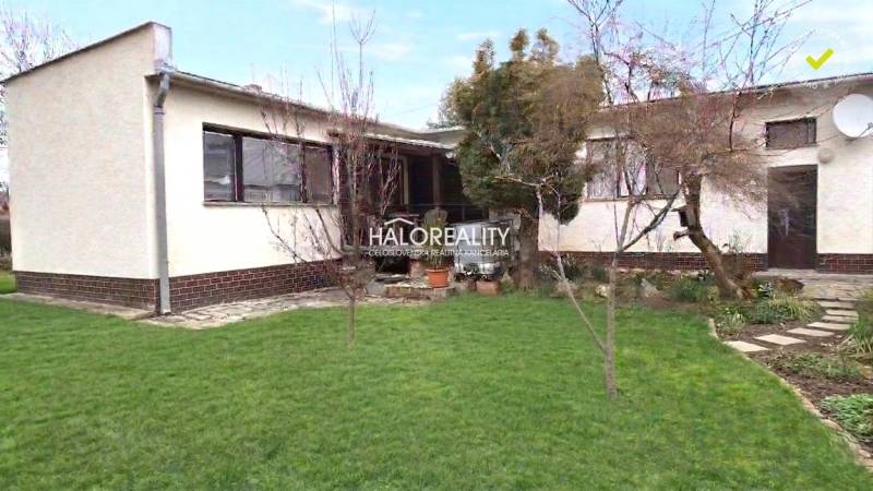 Rodinný dům v Poltáři se zahradou a stromy, upravený trávník.