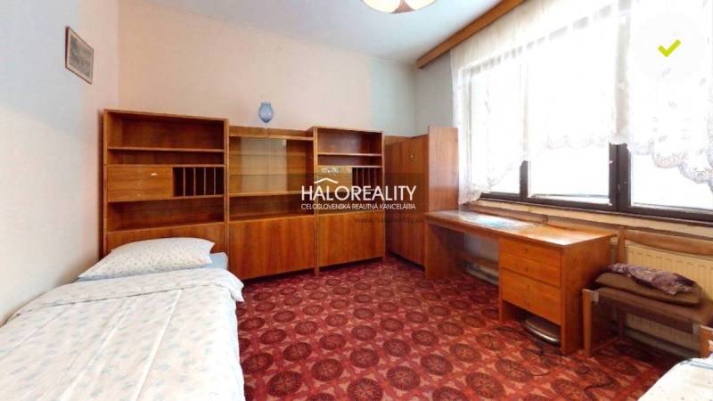 Pokoj s kobercovou podlahou, dřevěným nábytkem v rodinném domě.