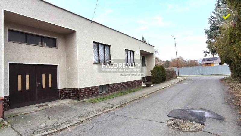 Rodinný dům ve městě Poltár s rovnou střechou a garáží u cesty.