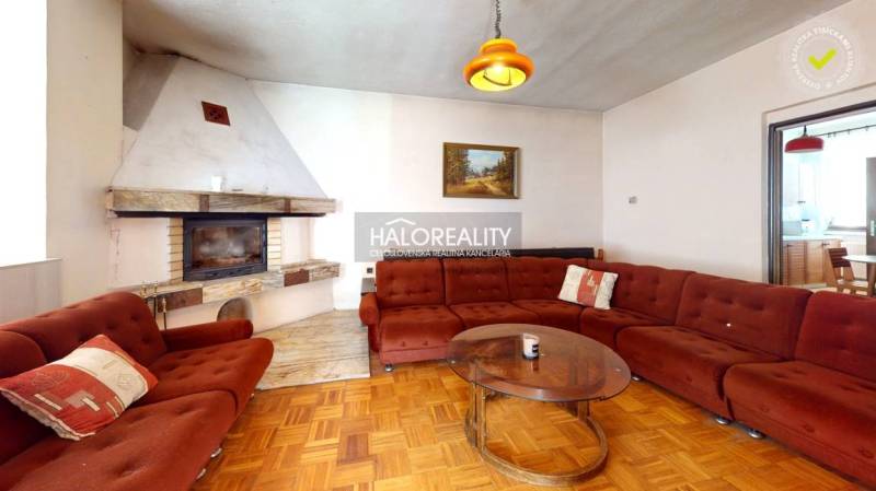 Obývací pokoj s krbem a pohovkou v rodinném domě, s podlahou s dřevěným dekorem.