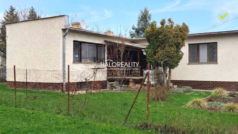 Rodinný dům v Poltáři obklopený trávníkem a stromy, s terasou a plotem.