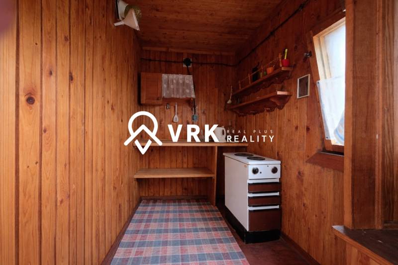 Dřevěné stěny, sporák a police v interiéru s podlahou s dřevěným dekorem.