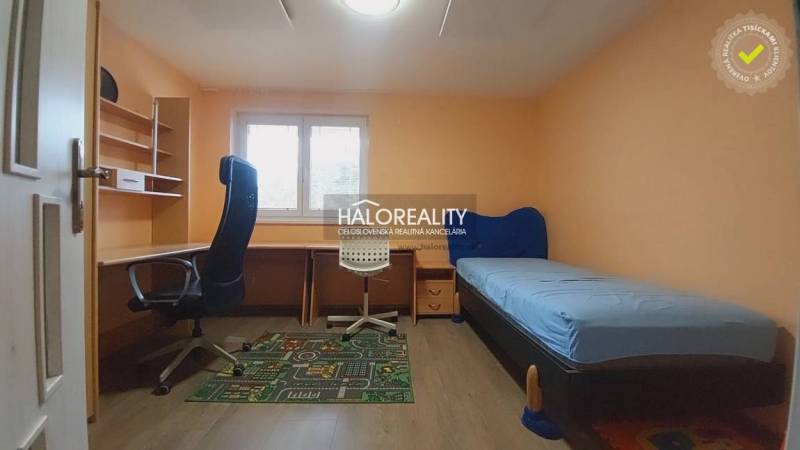 Dětský pokoj v rodinném domě se stolem, postelí a kancelářskou židlí.