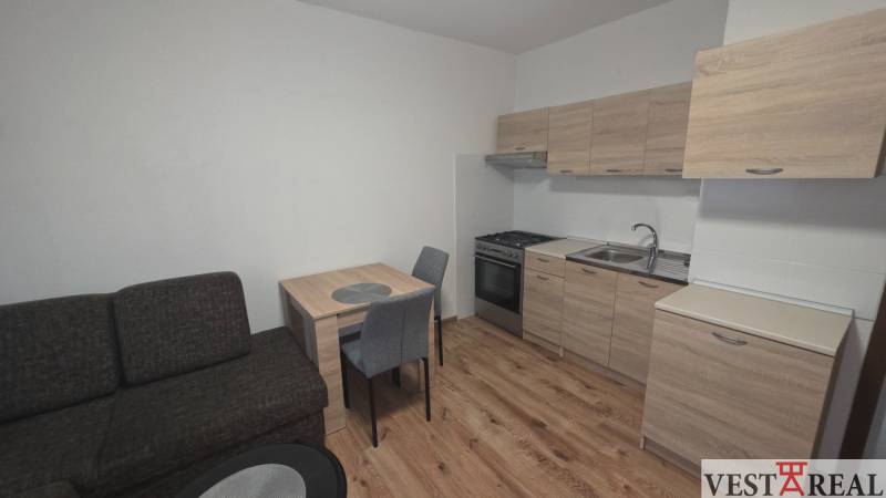 Kuchyně v 1-pokojovém bytě s dřevěným dekorem podlahy a nábytku.