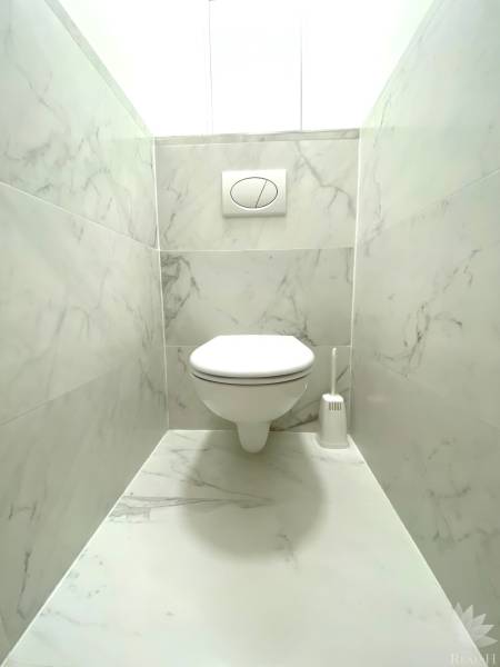 Koupelna se závěsným wc a mramorovým obkladem v 2-pokojovém bytě.
