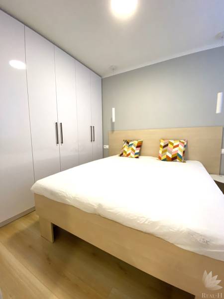 Ložnice s manželskou postelí, barevnými polštáři a skříní, 2pokojový byt.