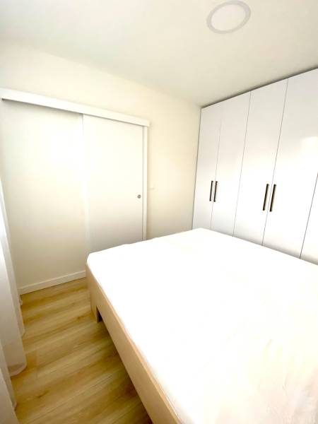 Ložnice v 2pokojovém bytě s postelí a velkou vestavěnou skříní.