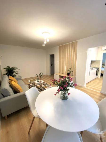 Jídelna v 2-pokojovém bytě s bílým stolem a podlahou s dřevěným dekorem.