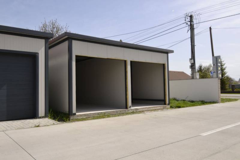 Garáže v Michali na Ostrově se dvěma otevřenými vjezdy, vedle cesty a plotu.