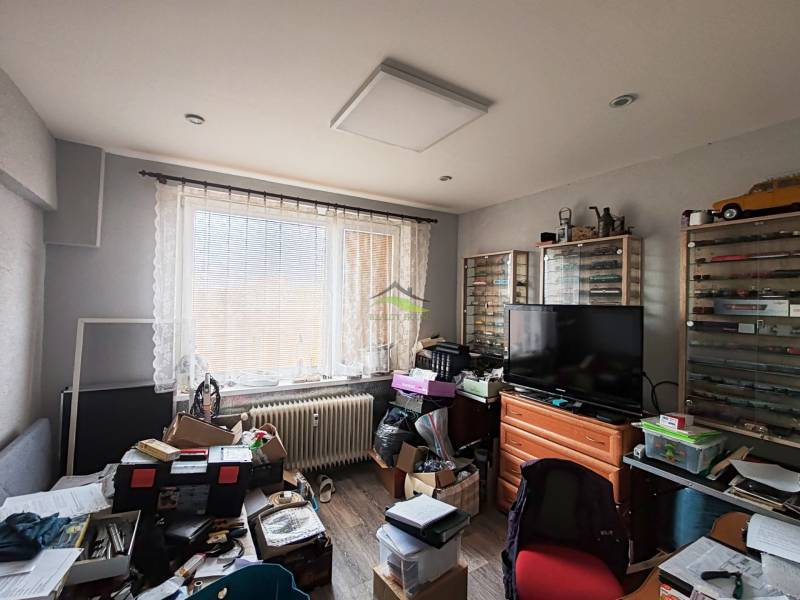 Pokoj ve 4pokojovém bytě s podlahou s dřevěným dekorem a množstvím úložných boxů.