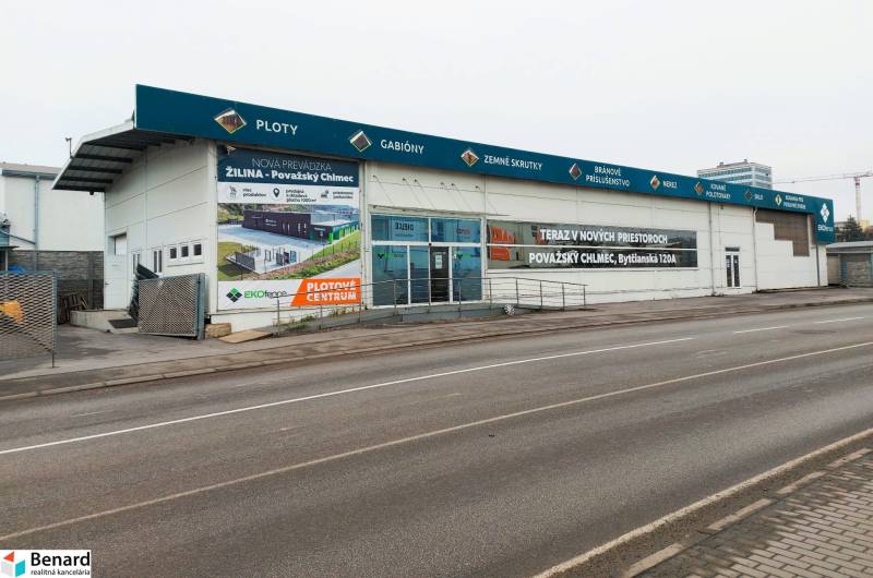 Obchodní prostory na Kamennej ulici v Žilině s reklamními nápisy a prázdným parkovištěm.