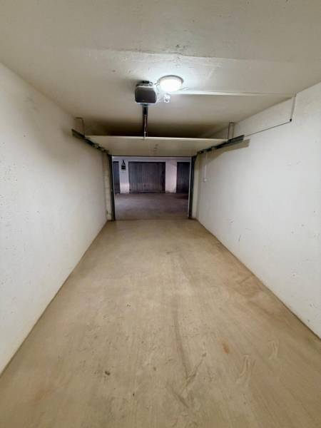 Uzavřený prostor garáže s betonovou podlahou a osvětlením.