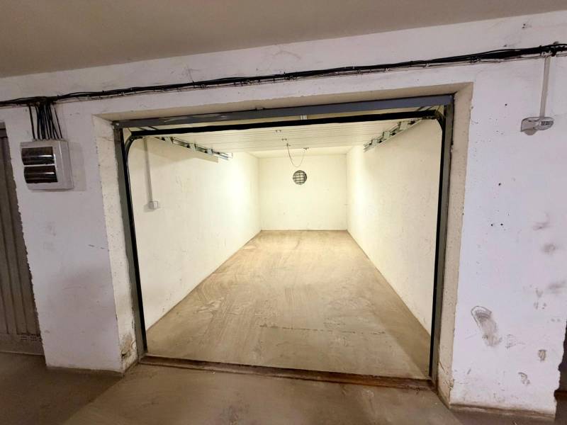 Prázdné garáže s betonovou podlahou a jednoduchým osvětlením.