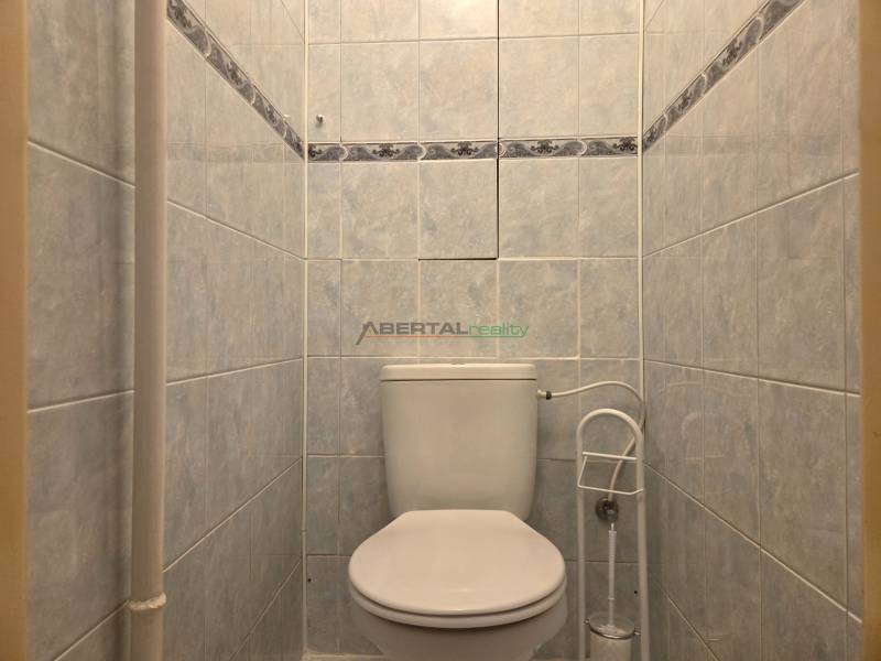 Toaleta s bílým keramickým obkladem v 3-pokojovém bytě.