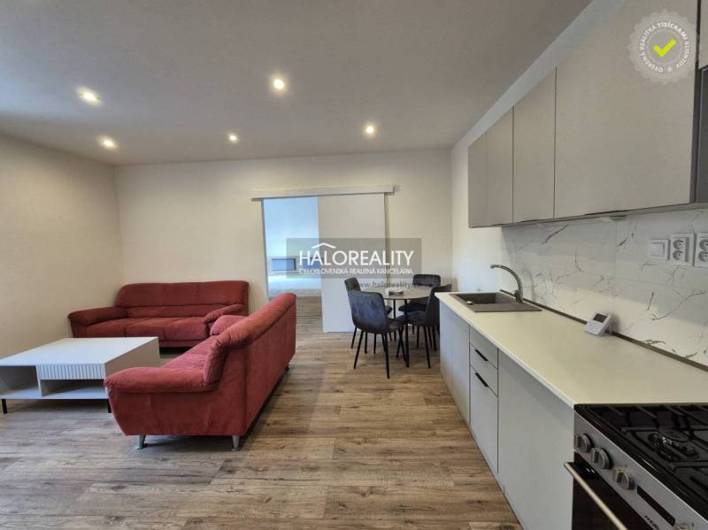 Obývací pokoj v 2-pokojovém bytě s pohovkou a podlahou s dřevěným dekorem.