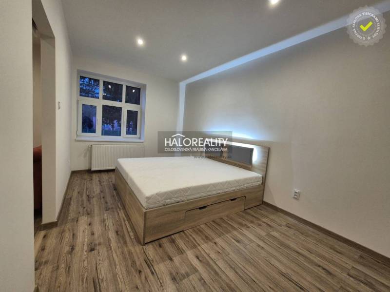 Ložnice v 2pokojovém bytě s postelí a podlahou s dřevěným dekorem.