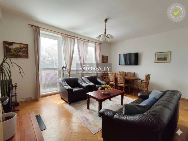 Obývací pokoj s koženými sedačkami a televizorem, s podlahou s dřevěným dekorem.