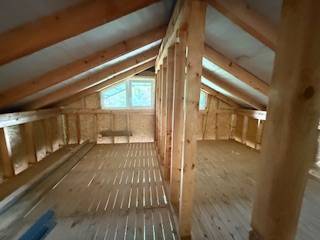 Podkrovní prostor chaty s dřevěnými trámy a podlahou s dřevěným dekorem.