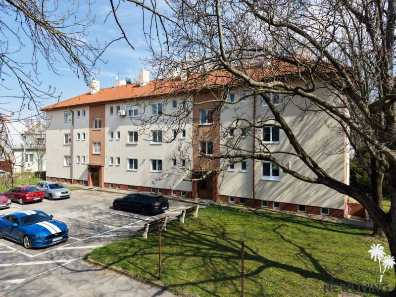 Bytový dům s parkovištěm a stromy na Vajanského ulici v Piešťanech.