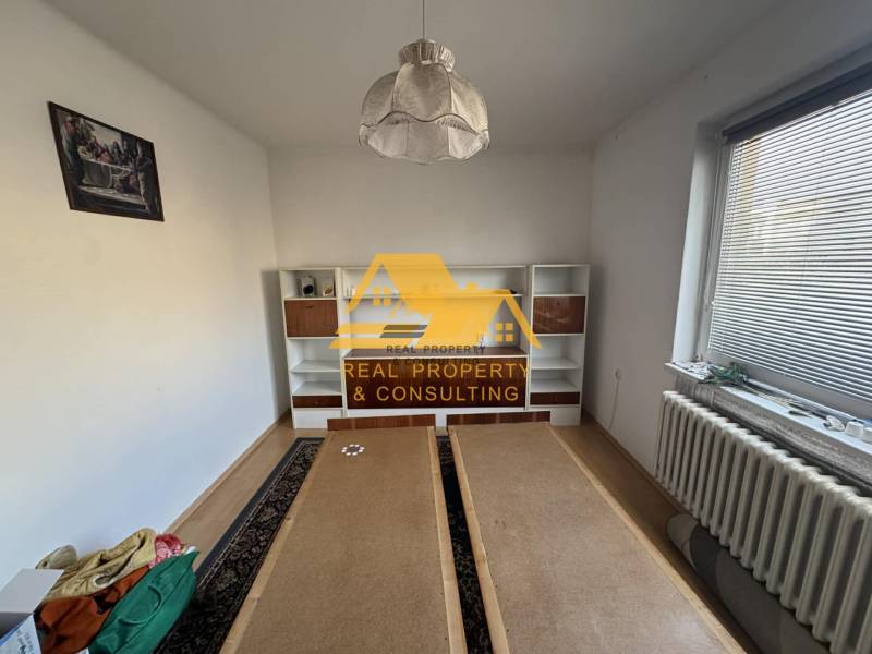 Pokoj s bílou stěnou, policovou skříní a podlahou s dřevěným dekorem v rodinném domě.