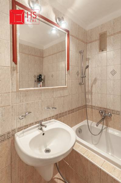 Koupelna s vanou, umyvadlem a zrcadlem ve 3-pokojovém bytě.