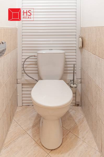 Toaleta s béžovými dlaždicemi v 3-pokojovém bytě, v čistém a jednoduchém designu.