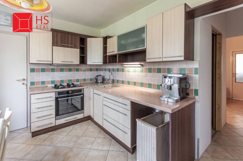 Kuchyně ve 3-pokojovém bytě s funkční linkou a dlaždicovým obkladem na stěně.