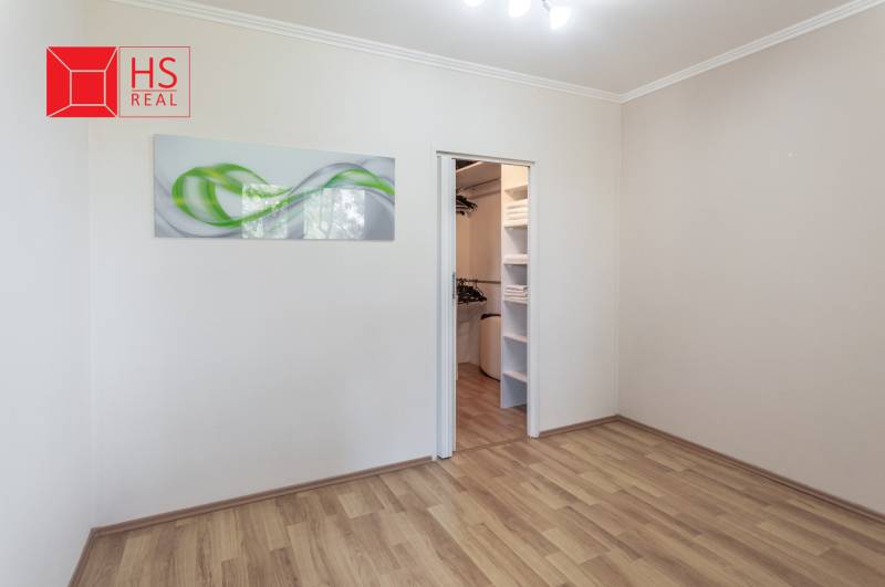 Pokoj s podlahou s dřevěným dekorem a vestavěnou skříní ve 3pokojovém bytě.