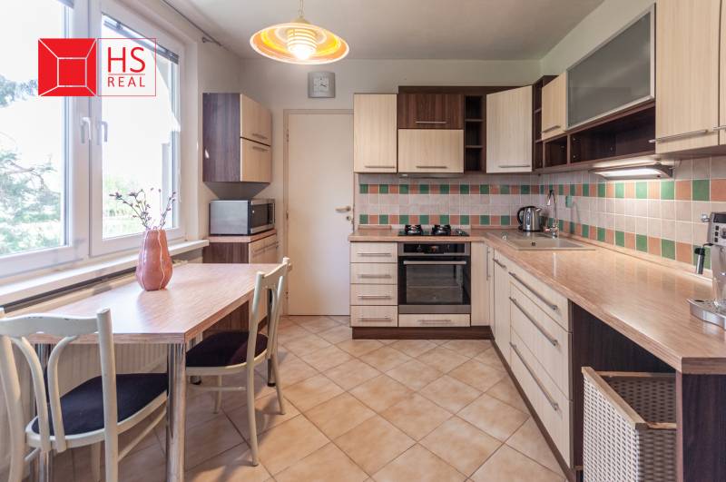 Kuchyně s mozaikovým obkladem a stolem v 3-pokojovém bytě je vybavena spotřebiči.