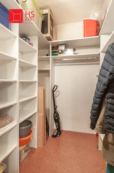 Šatník ve 3-pokojovém bytě s policemi a místem na zavěšení oděvů.