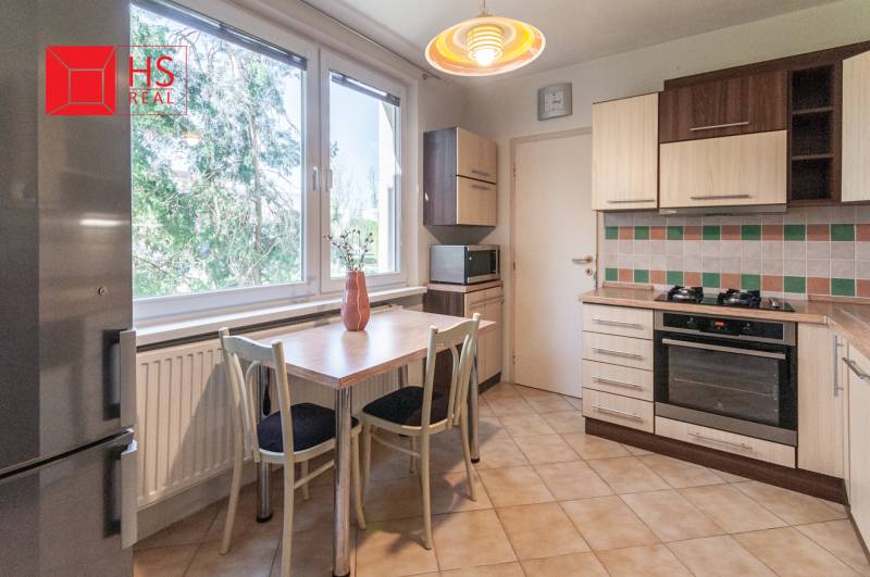 Kuchyně ve 3-pokojovém bytě s kachličkovanou stěnou a podlahou s dřevěným dekorem.