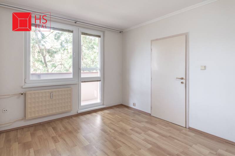 Pokoj ve 3-pokojovém bytě s podlahou s dřevěným dekorem a velkými okny.