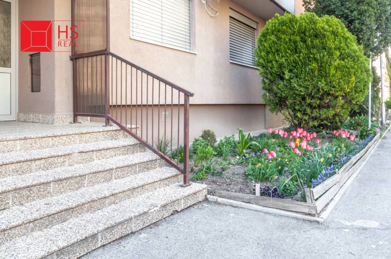 Vchod do 3-pokojového bytu na Nábrežní ulici v Nových Zámcích s květinovou zahrádkou.