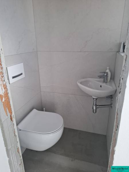 Malá koupelna v rodinném domě s pračkou a umyvadlem.
