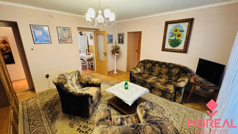 Obývací pokoj s křesly, gaučem a kobercem ve 3pokojovém bytě.