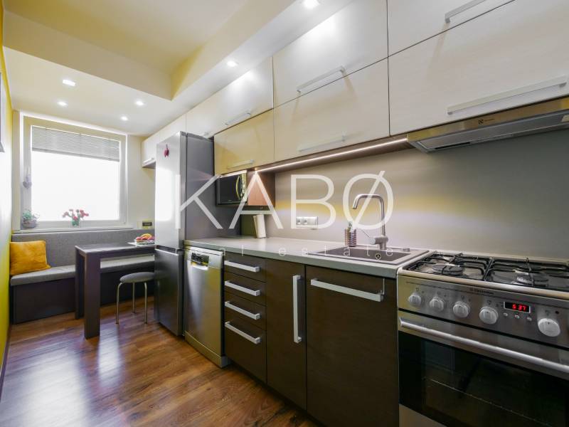 Kuchyně v 3-pokojovém bytě s podlahou s dřevěným dekorem a rohovým sezením.