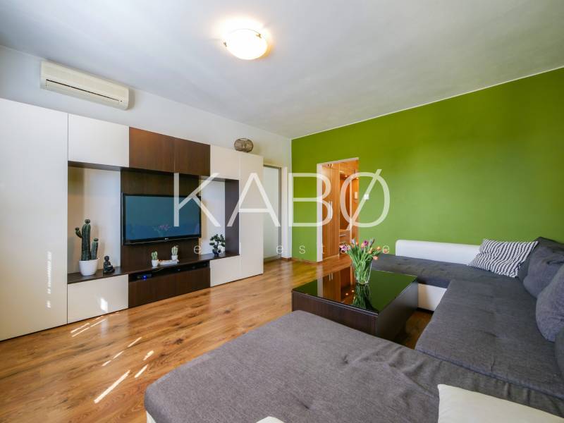 Obývací pokoj ve 3-pokojovém bytě s podlahou s dřevěným dekorem a zelenou stěnou.