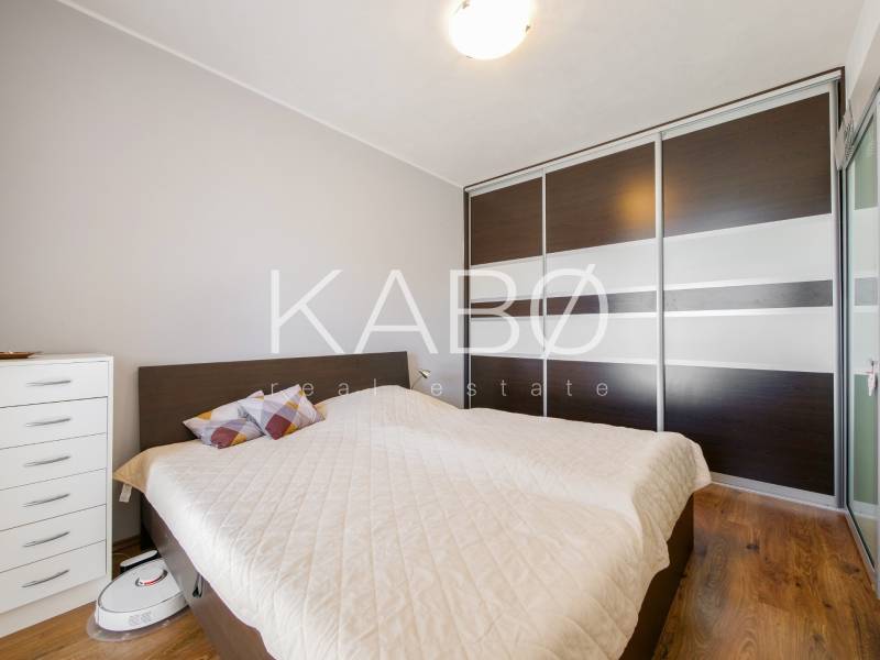 Ložnice v 3-pokojovém bytě s podlahou s dřevěným dekorem a vestavěnou skříní.