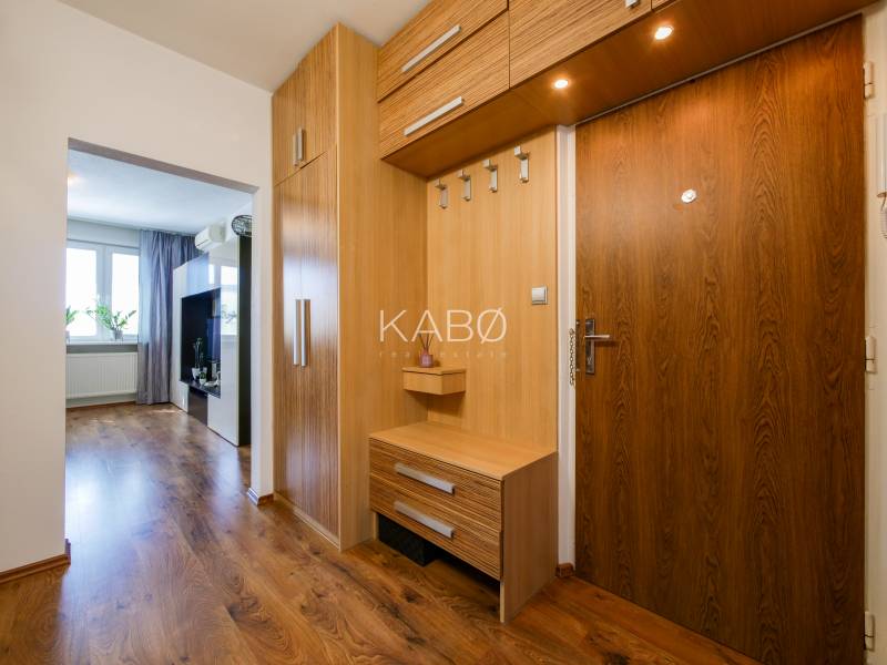 Interiér 3-pokojového bytu s chodbou, dřevěnými skříňkami a podlahou s dřevěným dekorem.