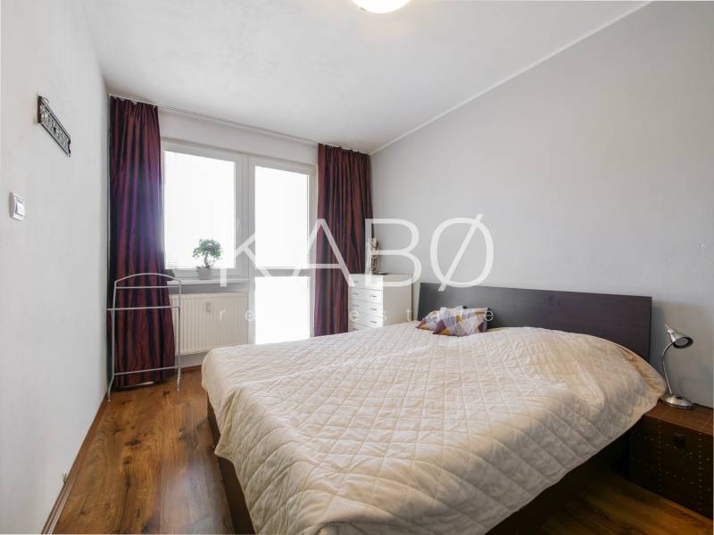 Ložnice ve 3pokojovém bytě s podlahou s dřevěným dekorem a postelí.