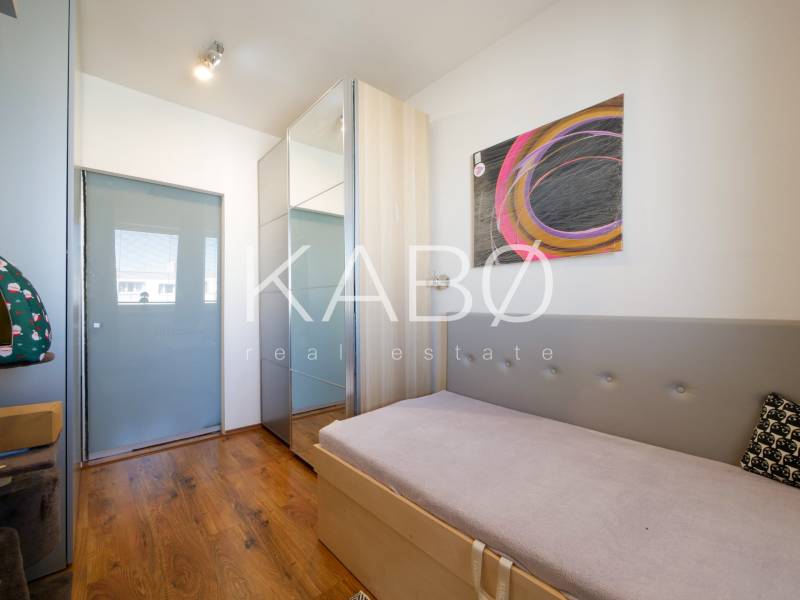 Dětský pokoj ve 3-pokojovém bytě s podlahou s dřevěným dekorem a abstraktním uměním na stěně.