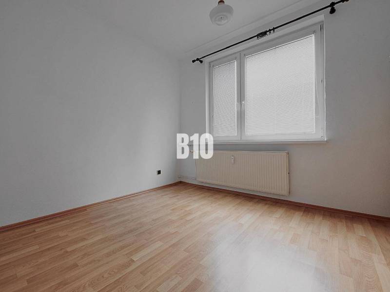 Prázdný pokoj se stěnami v 3-pokojovém bytě, podlaha s dřevěným dekorem, velké okno.