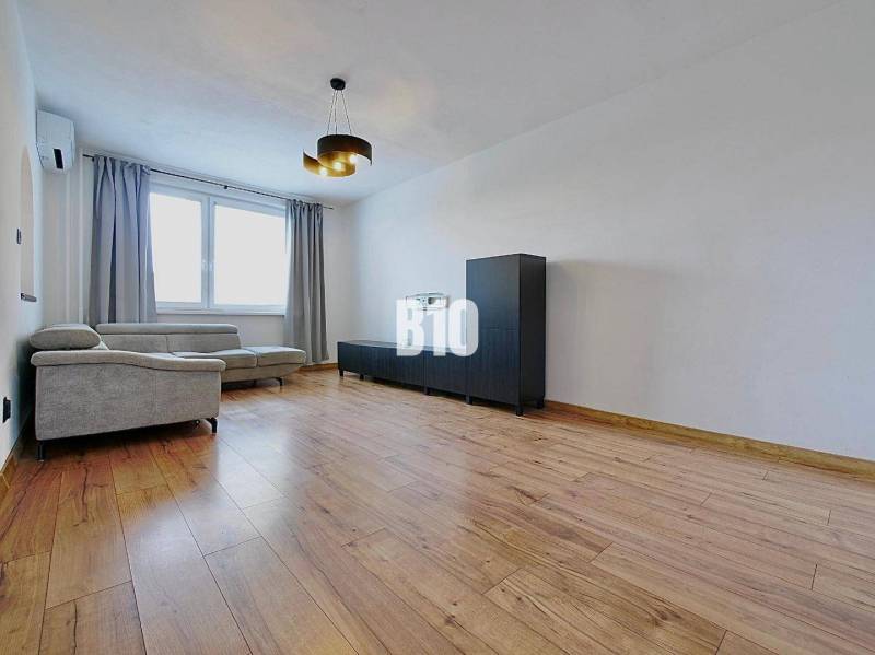 Obývací pokoj ve 3-pokojovém bytě s pohodlnou sedačkou a podlahou s dřevěným dekorem.