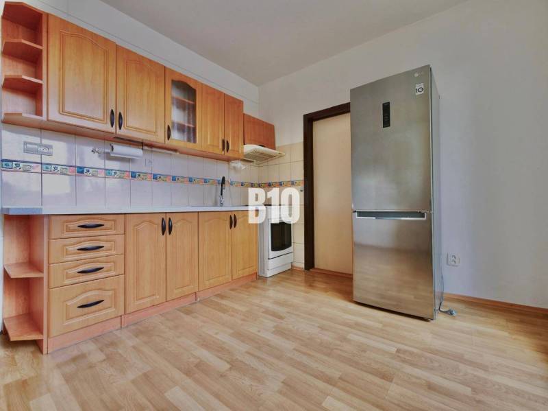 Kuchyně s dřevěnými skříňkami a podlahou s dřevěným dekorem v 3-pokojovém bytě.